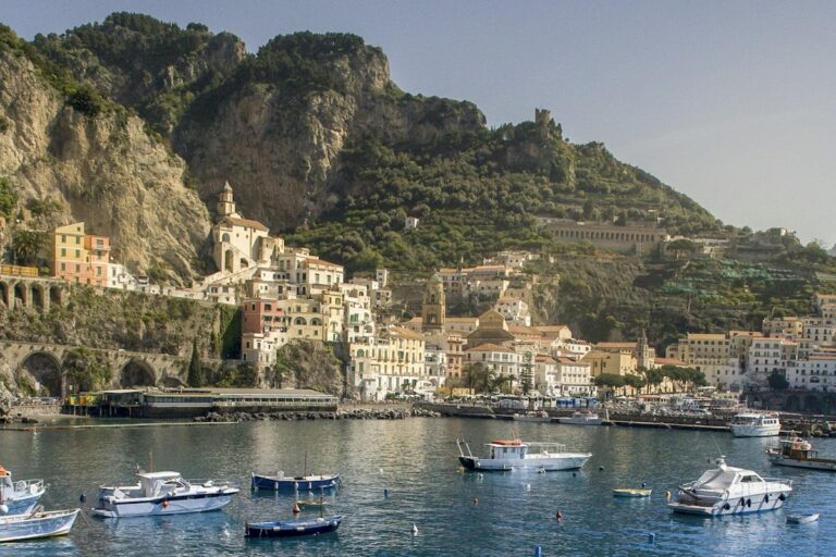 Best boat tours in Italy: boats in the harbor of Amalfi below the cliffs