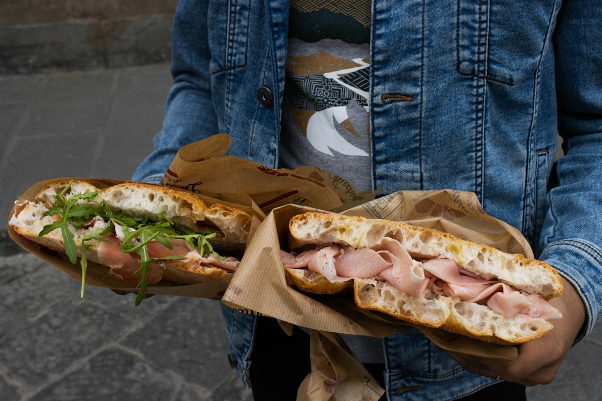 Best food tours in Florence: a traveler holding two Florentine sandwiches in the historic center