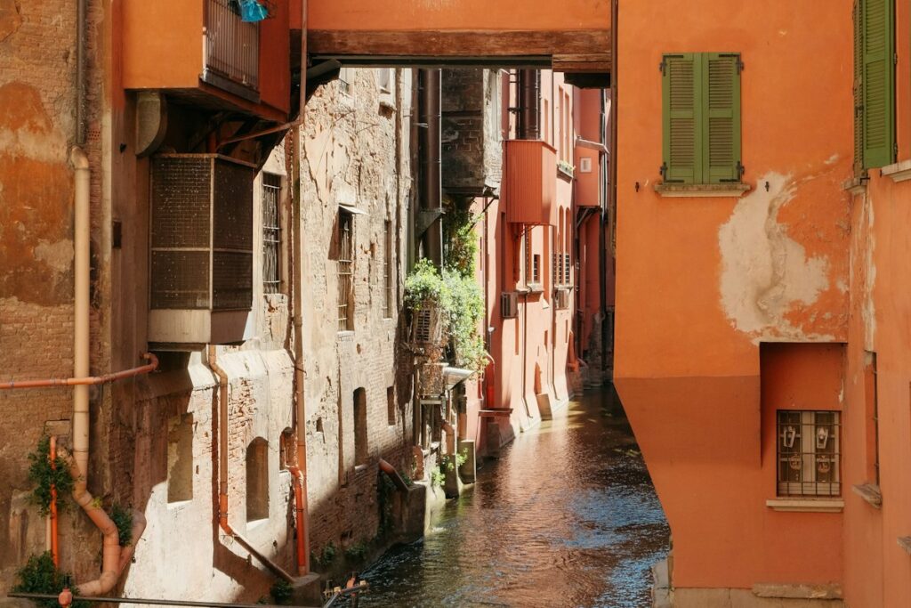 A canal between houses with green shutters in Bologna