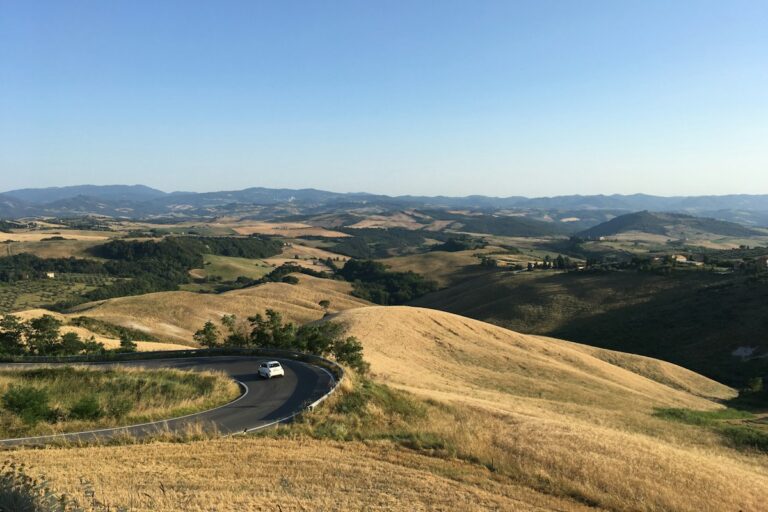 White car on the SR68 road near Volterra in Tuscany, a typical drive after a car rental in Italy