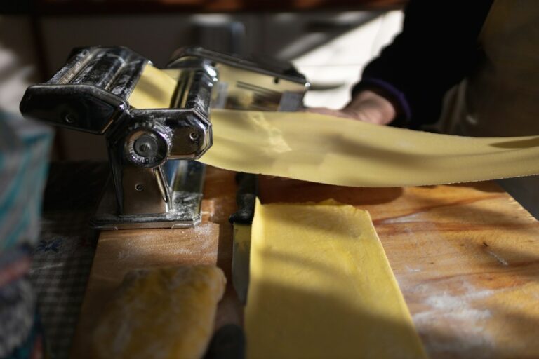 Rolling fresh pasta sheets through a pasta machine, a core skill in most cooking classes in Rome