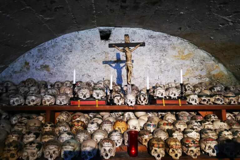 Skulls arranged beneath a crucifix in a crypt, a typical sight of dark tourism in Italy