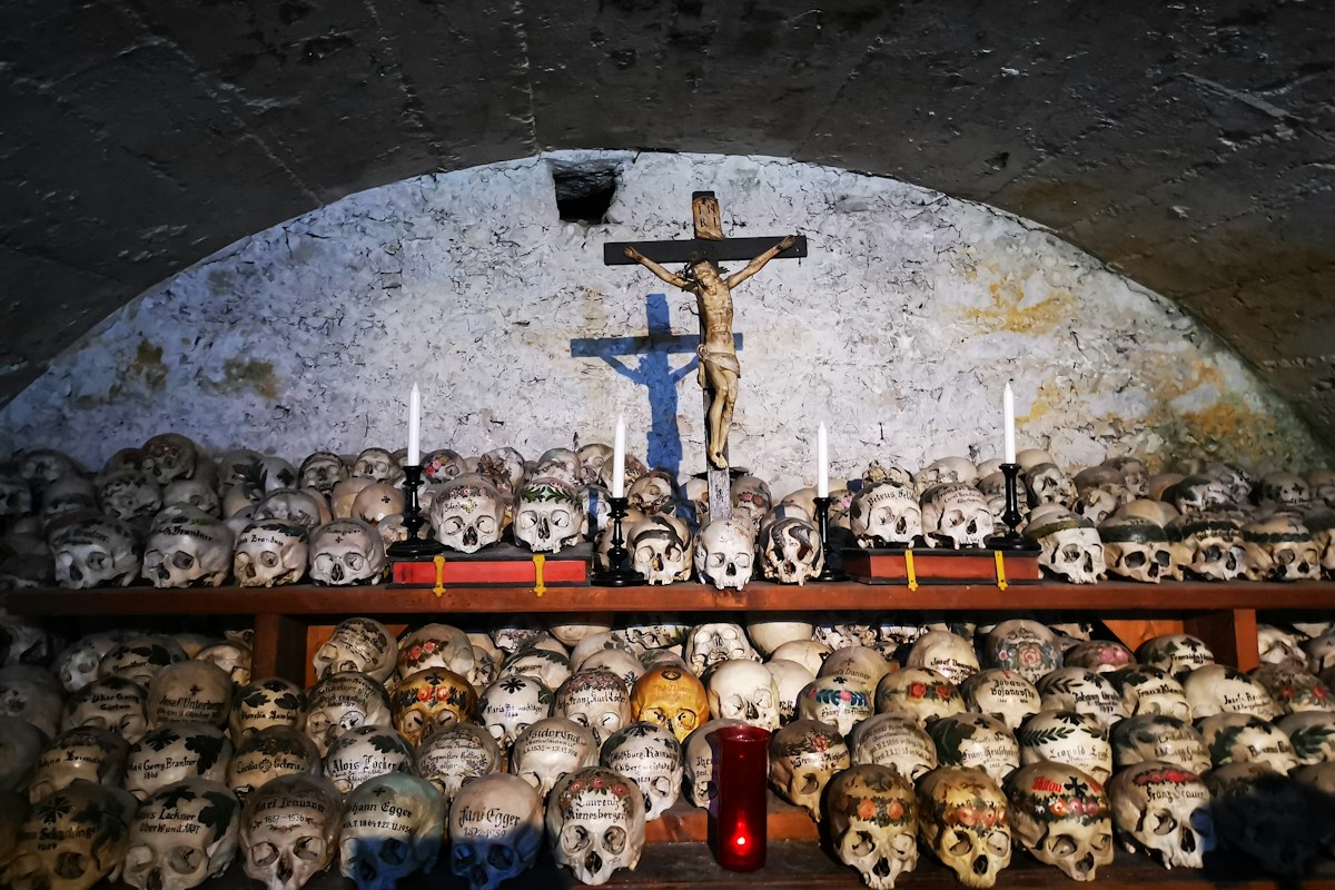 Skulls arranged beneath a crucifix in a crypt, a typical sight of dark tourism in Italy