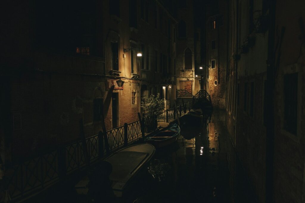 A dark, quiet canal in Venice at night, the mood of ghost tours in Italy