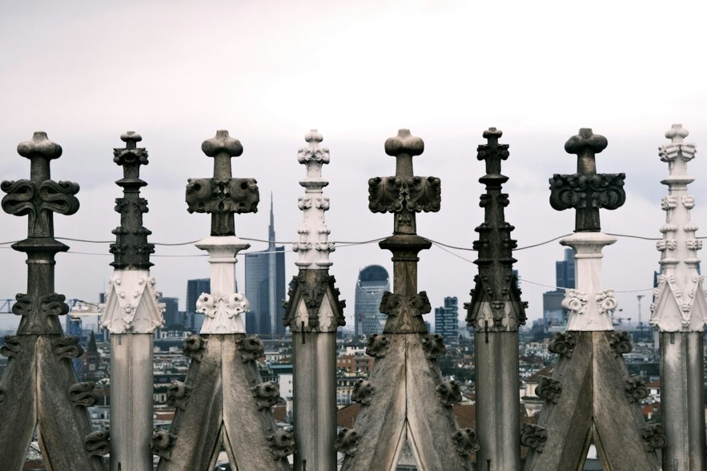 Rows of marble spires on the Milan Duomo rooftop with the city skyline behind