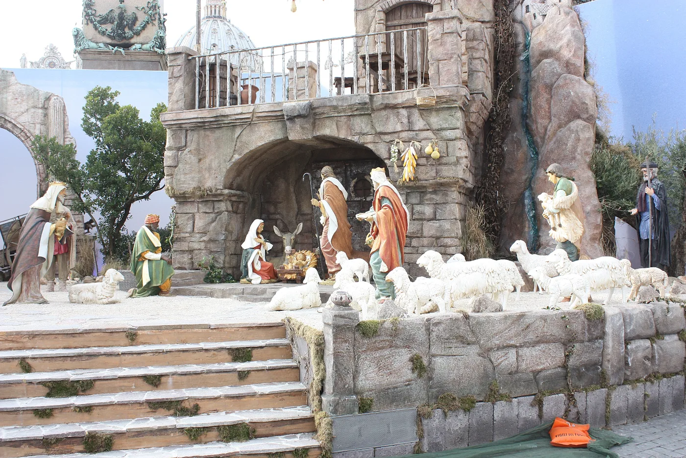 Life-size nativity figures and white sheep in front of a stone stable in St. Peter's Square