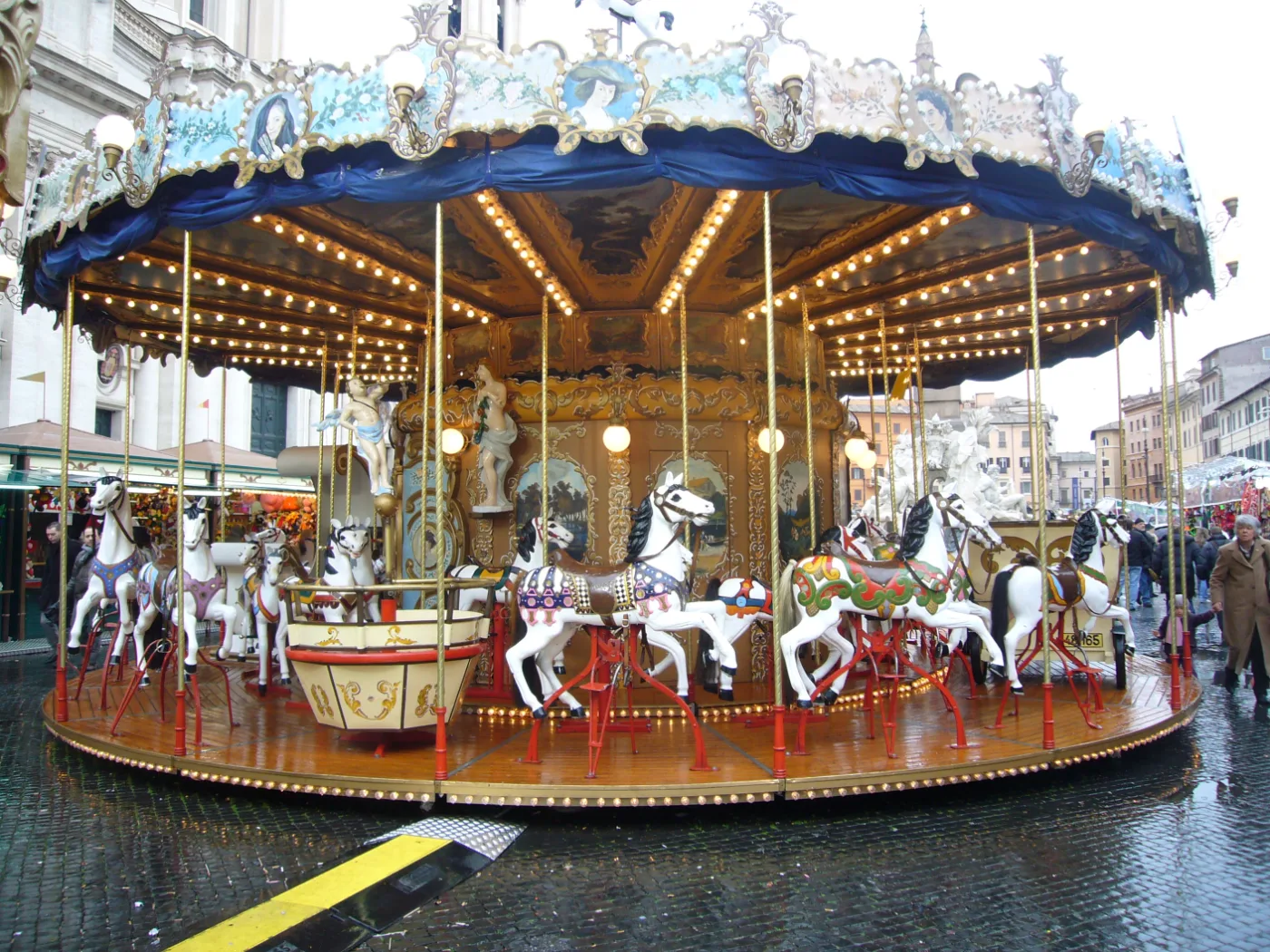 An old-fashioned carousel with white horses on the wet cobblestones of Piazza Navona