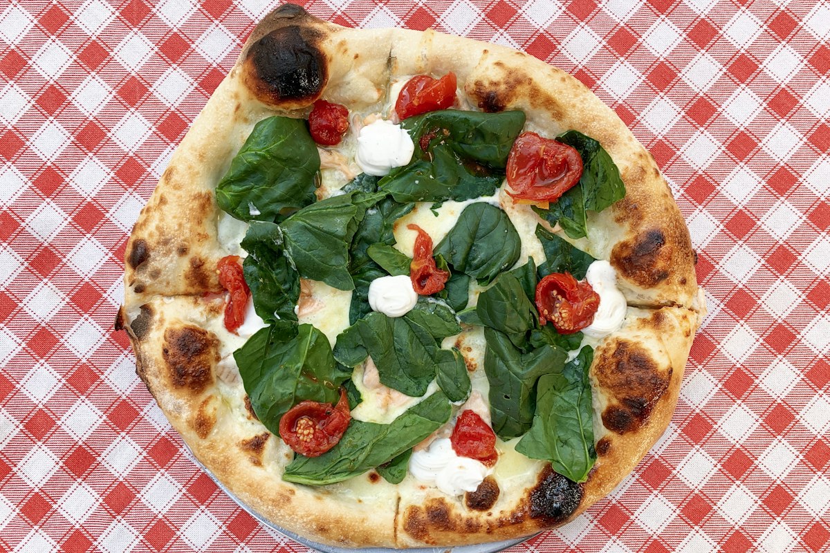 Pizza in Italy: a wood-fired pizza with spinach, cherry tomatoes and mozzarella in Naples