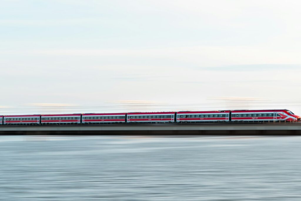 A train running along the water in Italy, as on the Rome to Venice train approach