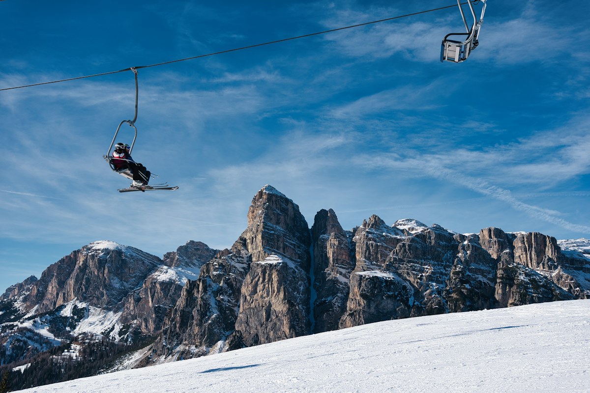 Skier and chairlift above jagged snowy peaks, the kind of terrain you find when you ski in Italy