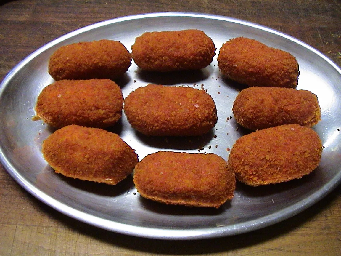A metal tray of golden fried supplì rice balls