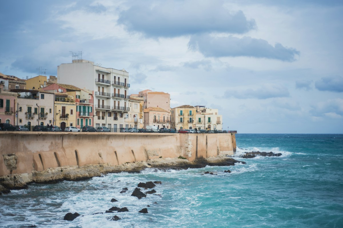 Pastel houses above the sea wall on the island of Ortigia in Syracuse