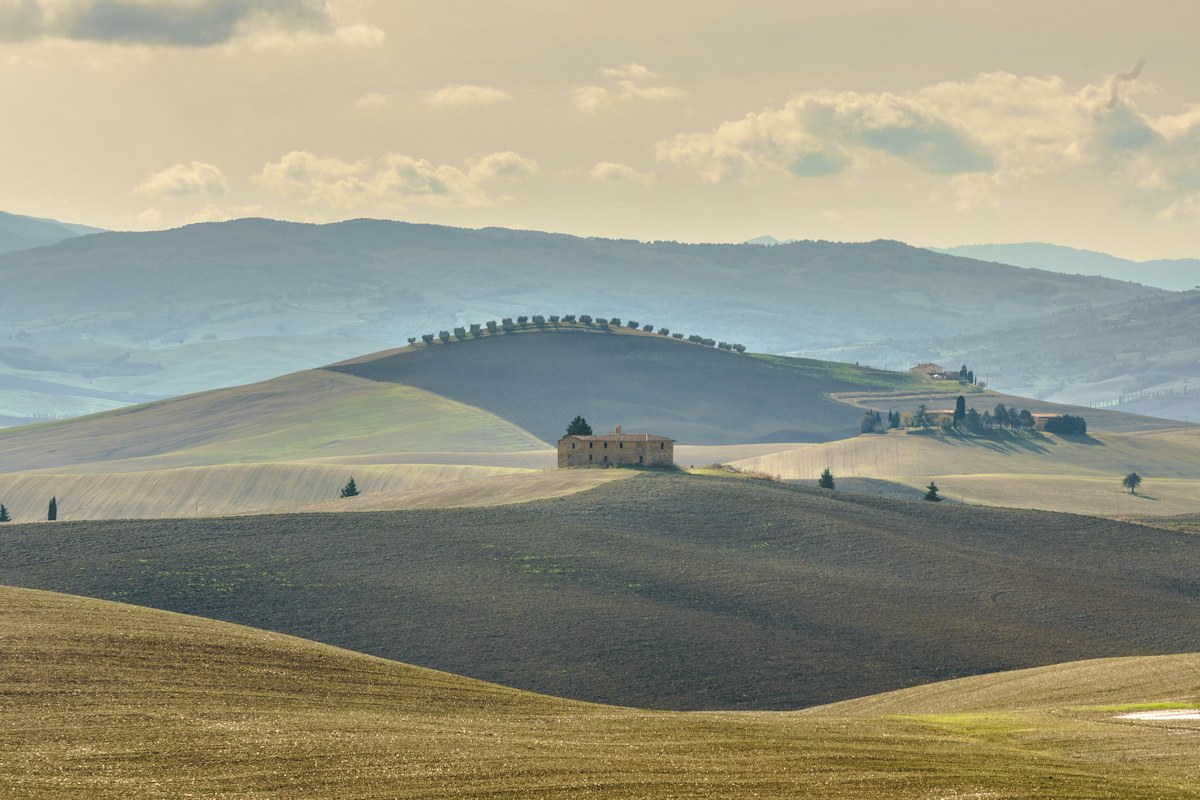 Rolling hills and a farmhouse in southern Tuscany, a classic stop on a Tuscany itinerary