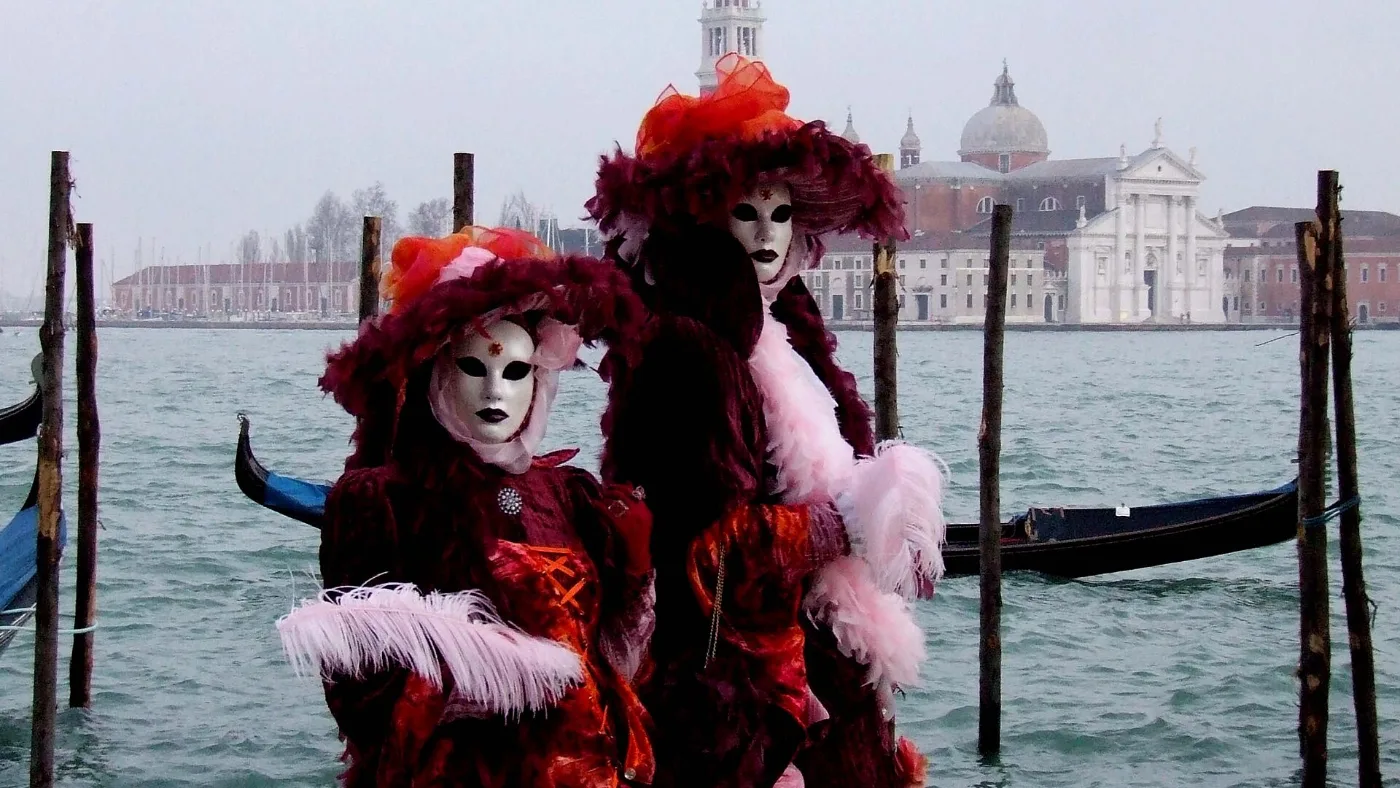 Masked figures in Carnival costume by the gondolas in Venice