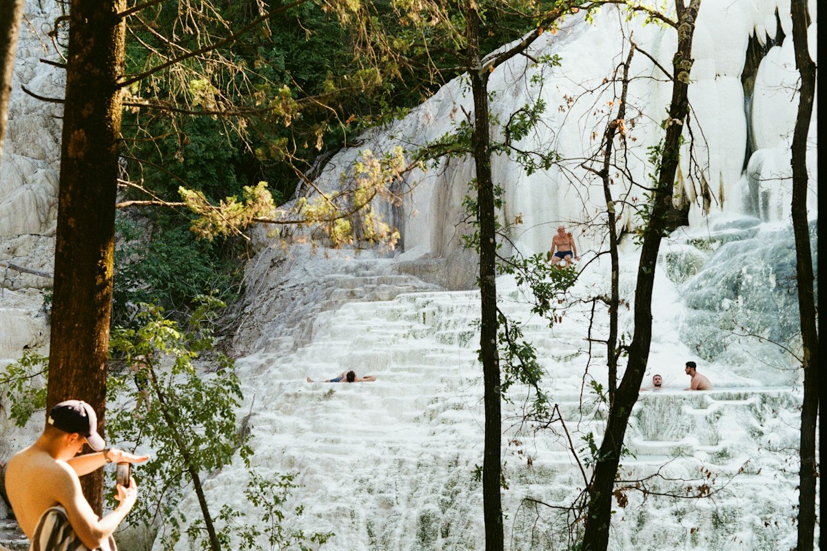 Wellness in Italy: bathers in the white travertine hot springs of Bagni San Filippo, Tuscany