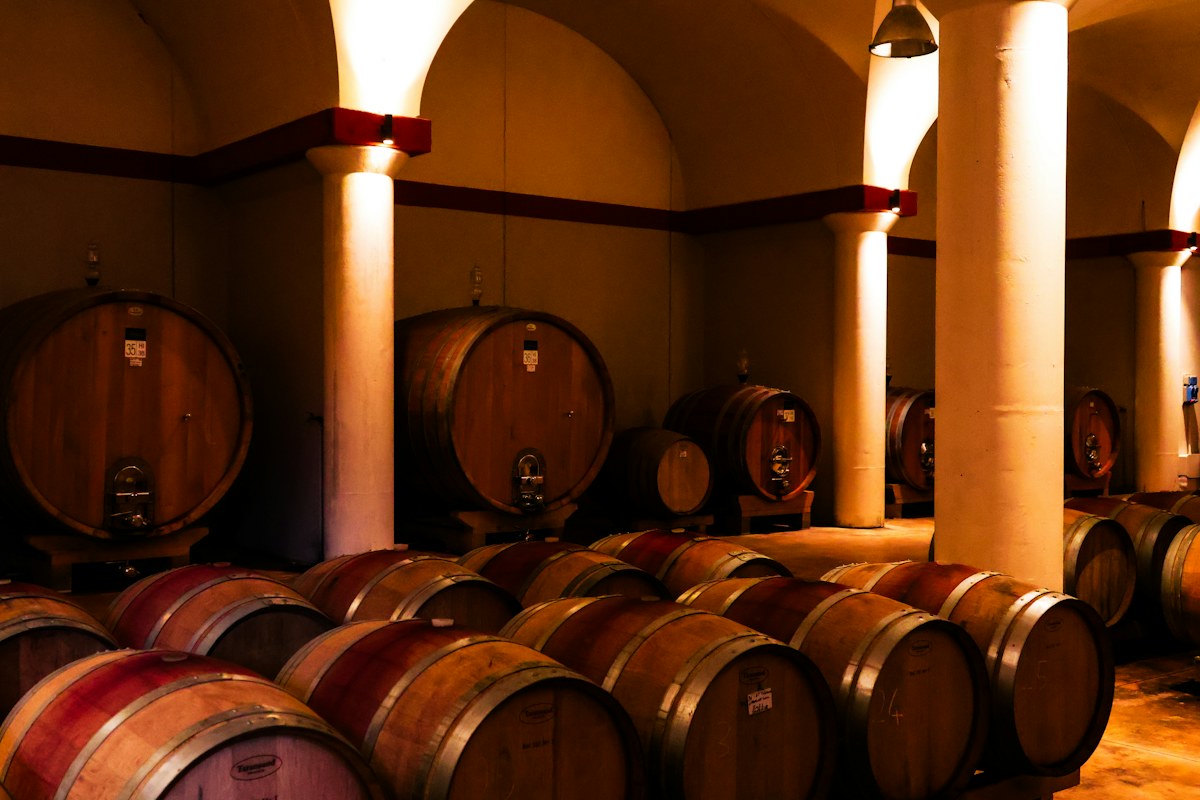 Oak barrels in a vaulted cellar, where many Italian wine brands age their wines