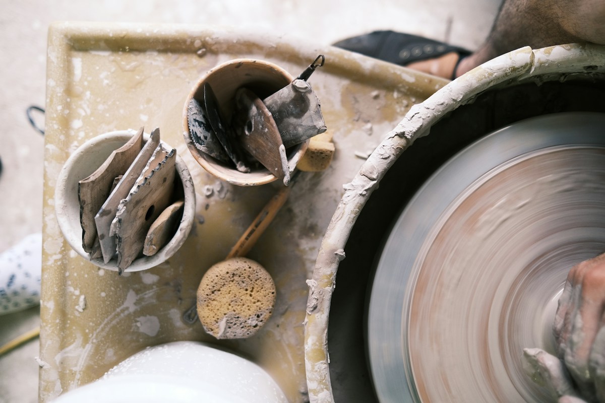 Hands shaping clay on a pottery wheel during an artisan workshop