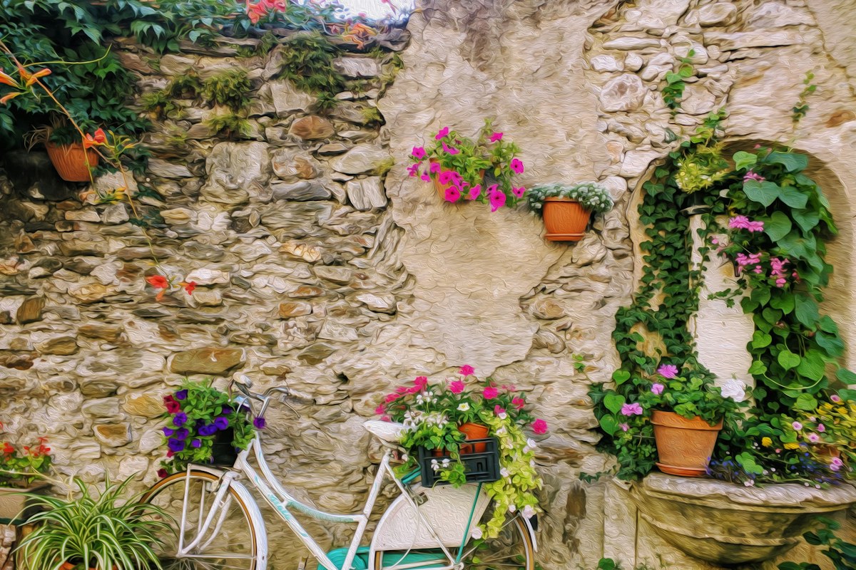 Flower pots and a bicycle against an old stone wall in Levico Terme
