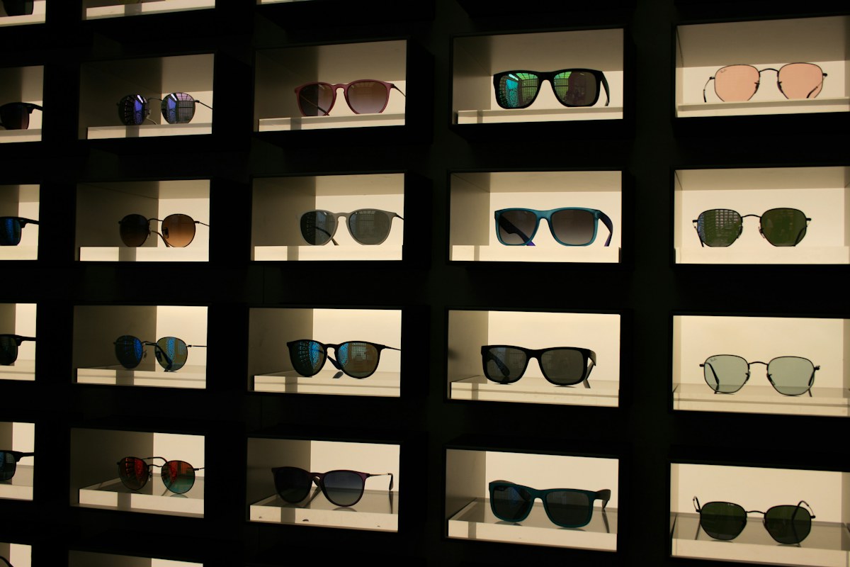 Rows of sunglasses on lit shelves in an optician’s shop in Florence